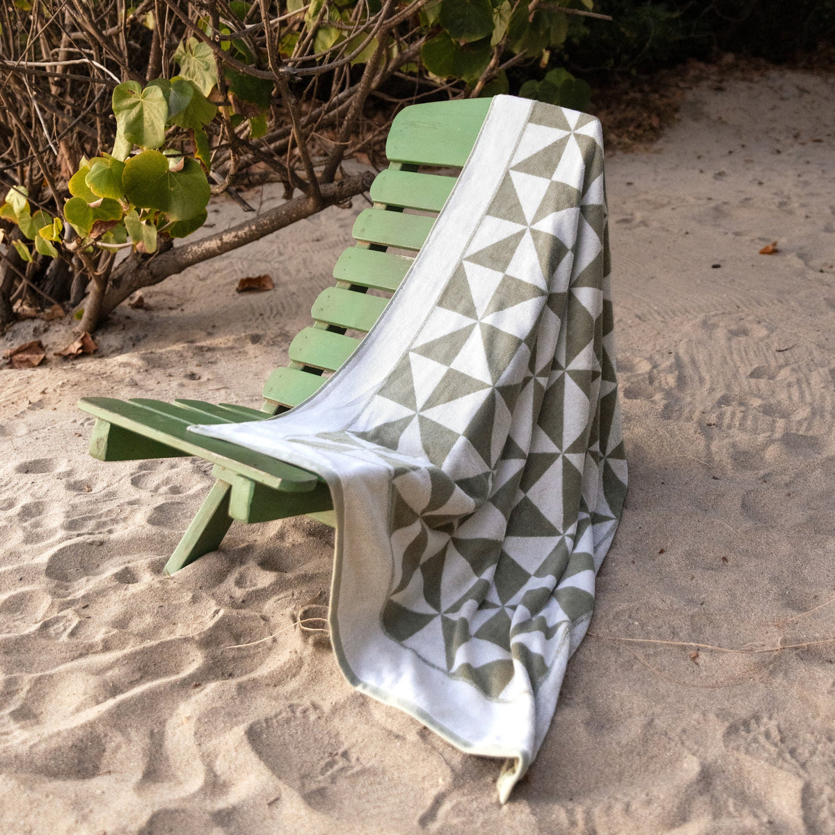 Sage green and ecru geometric cotton beach towel draped over a wooden chair