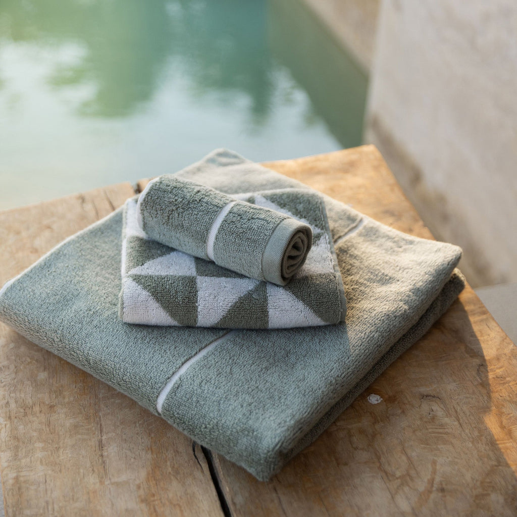 Folded light blue and cream cotton towels with geometric pattern on top