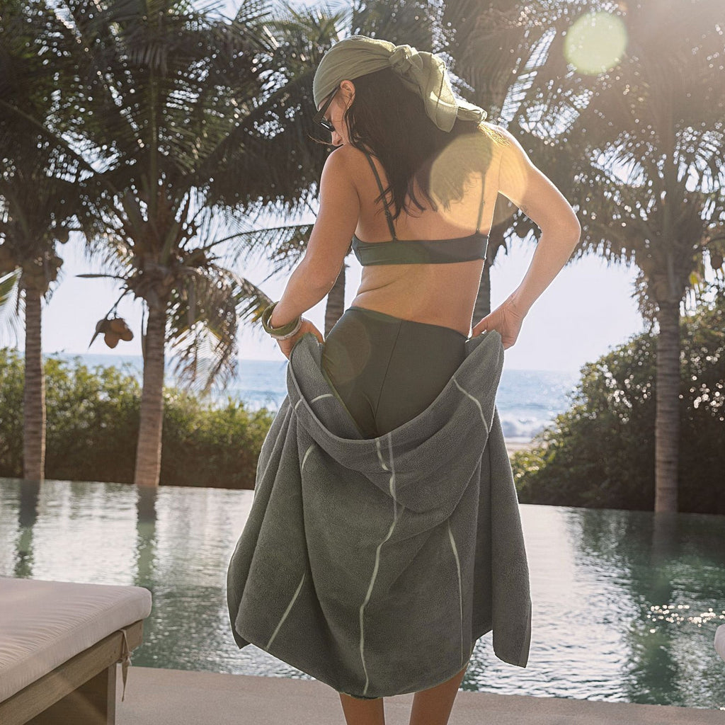 Sage green cotton towel wrap worn by person over shoulder, terry texture visible