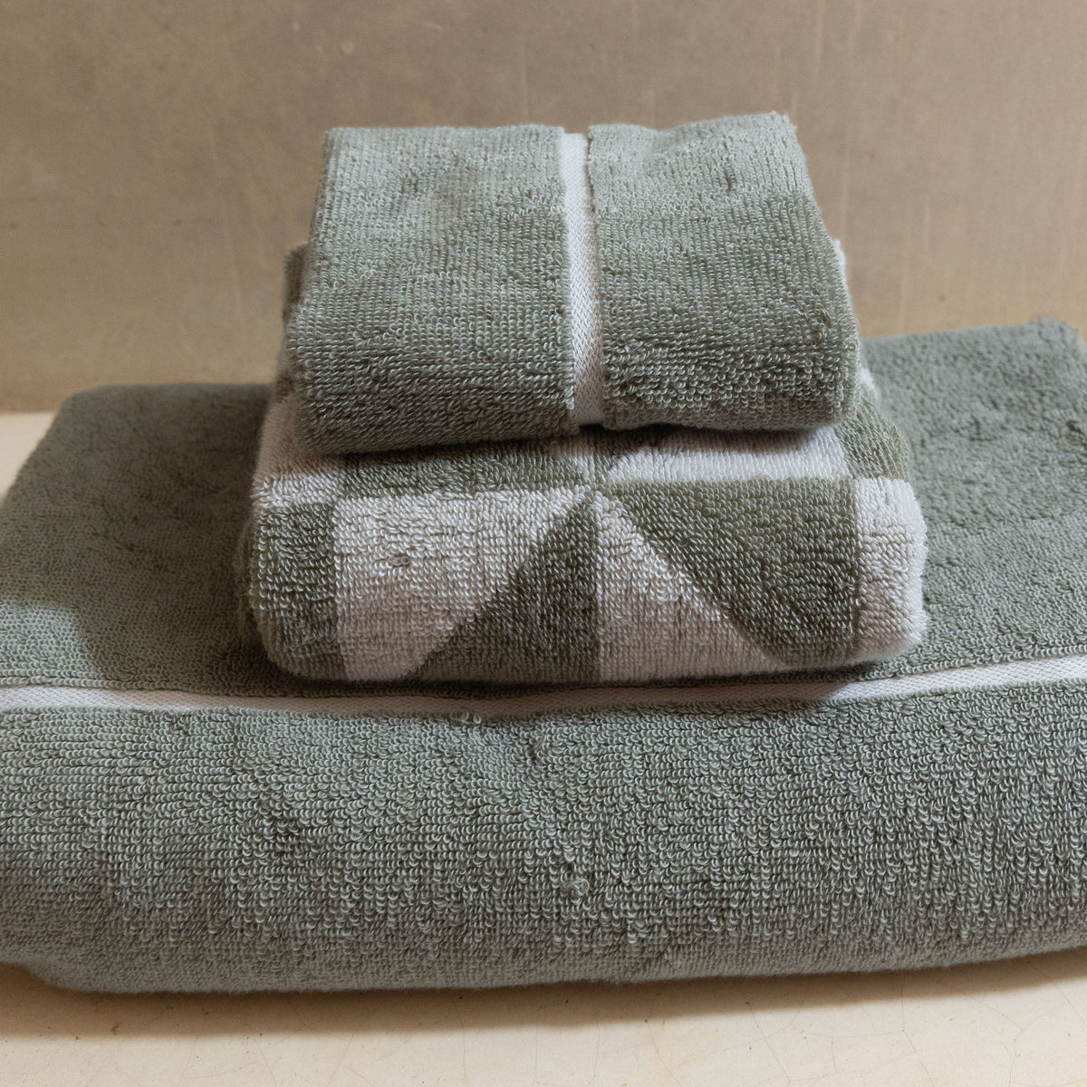 Sage green cotton bath towel with white stripe accents and rolled folded top towels