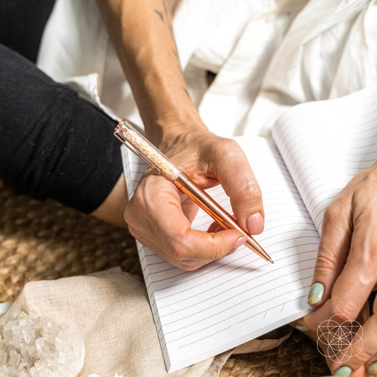 Copper manifestation pen writing in an open notebook, orange glitter inlay barrel