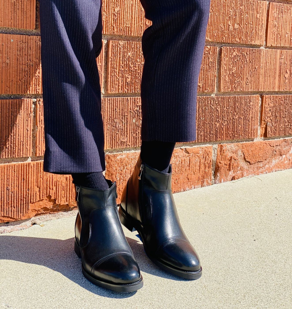 Black zipper ankle boots worn with dark pants, standing outdoors
