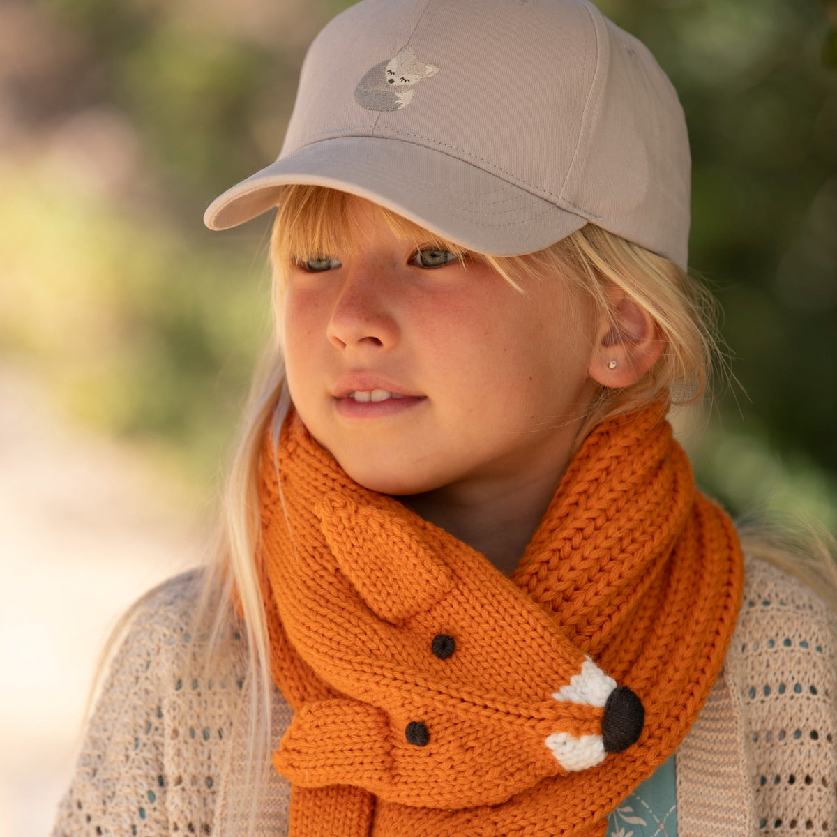 Orange knitted fox neck scarf on child, with button eyes and white paw accent