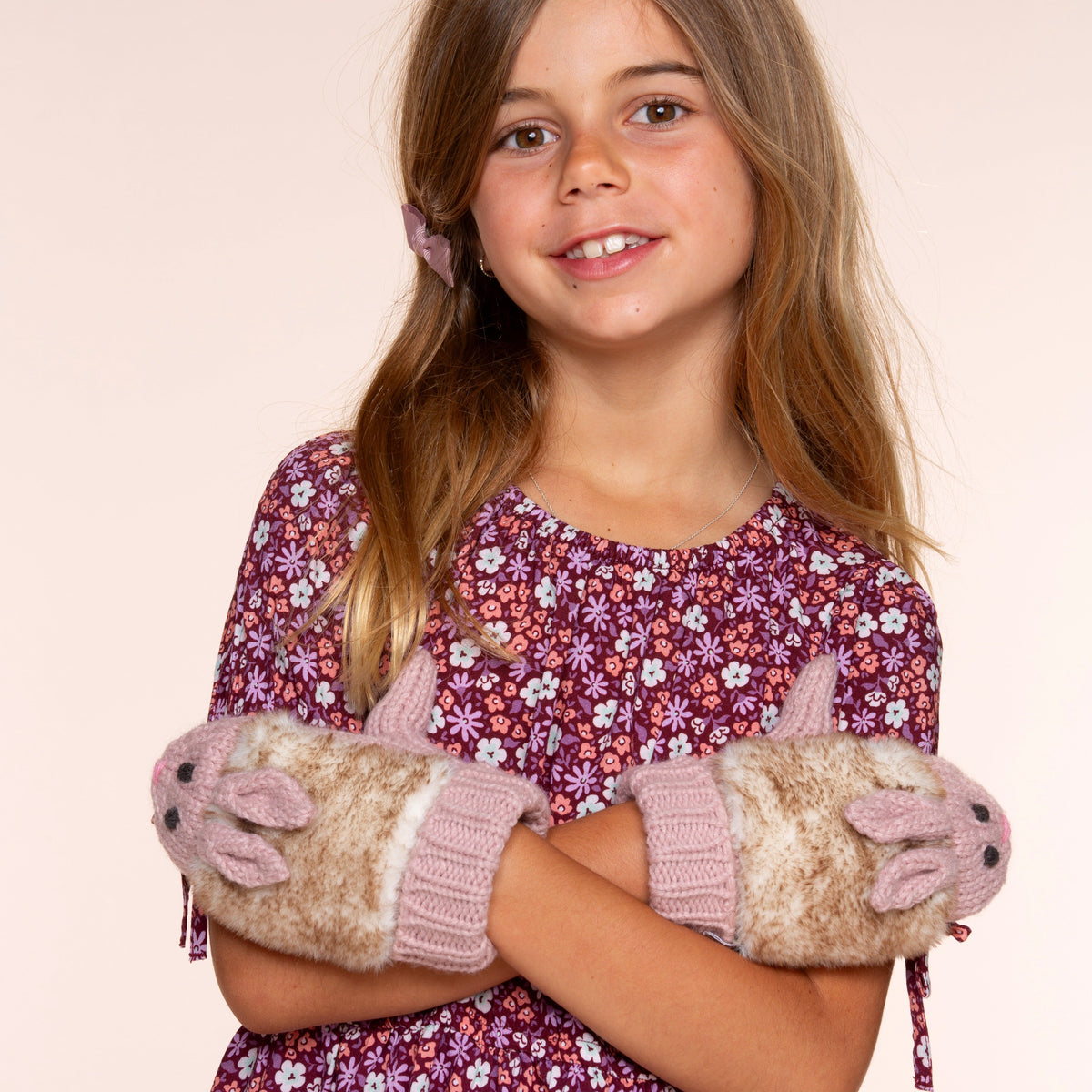 Mauve beanie with floral heart patch and pom-pom; rabbit-fleece mittens worn by child