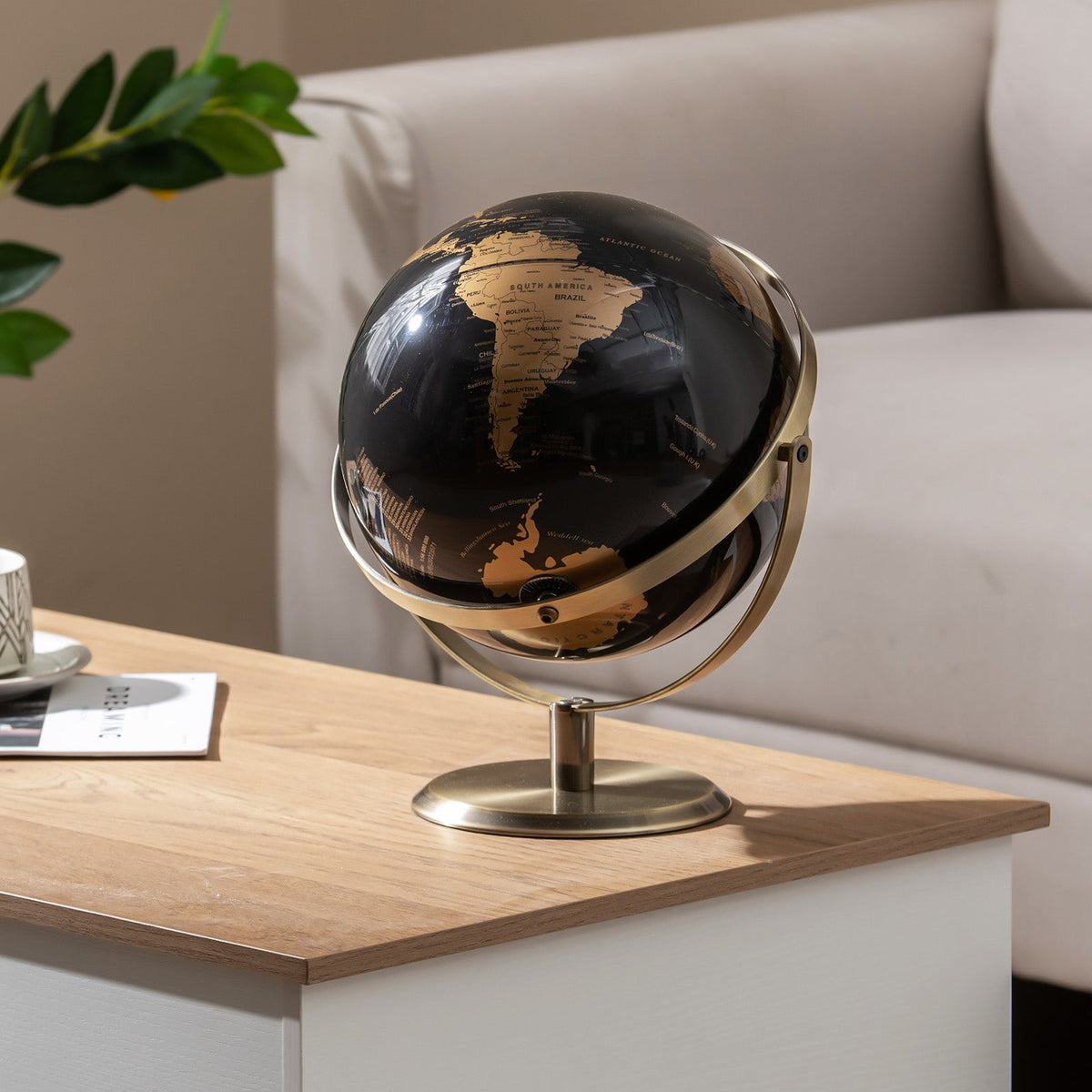 Metallic black world globe on gold metal stand with curved ring frame