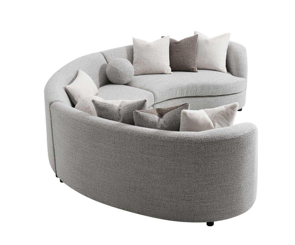 Light gray boucle sectional sofa with rounded ottoman chaise and multiple throw pillows