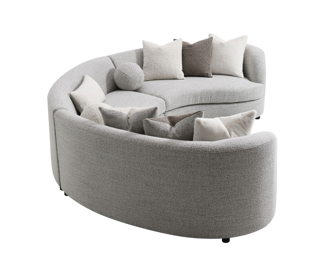 Light gray boucle sectional sofa with rounded ottoman chaise and multiple throw pillows