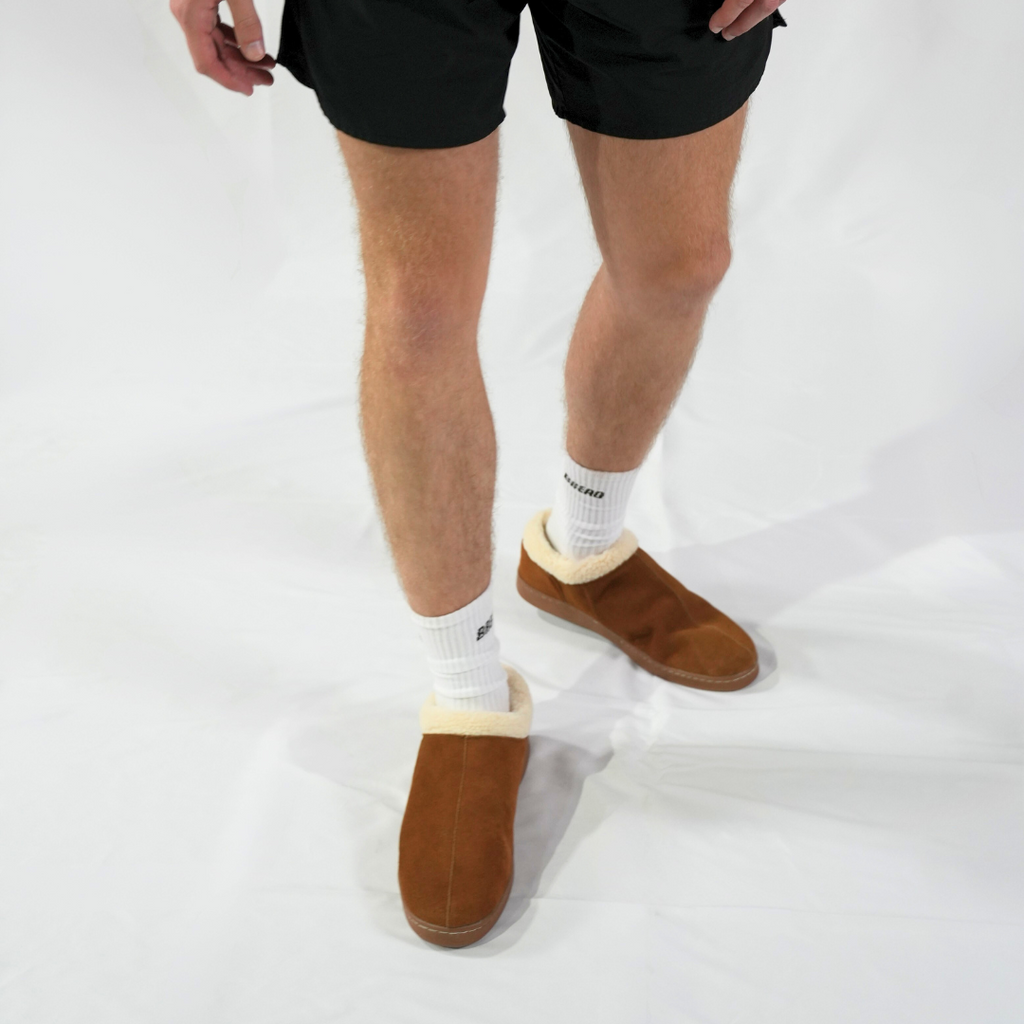 Men's Ashton slipper on model’s feet, brown suede with cream sherpa cuffs