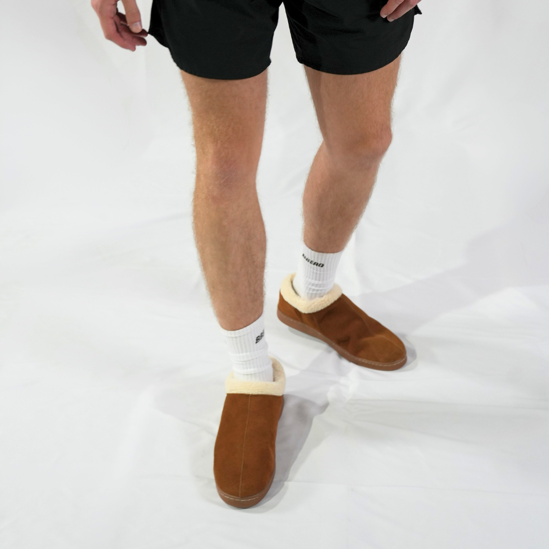 Men's Ashton slipper on model’s feet, brown suede with cream sherpa cuffs