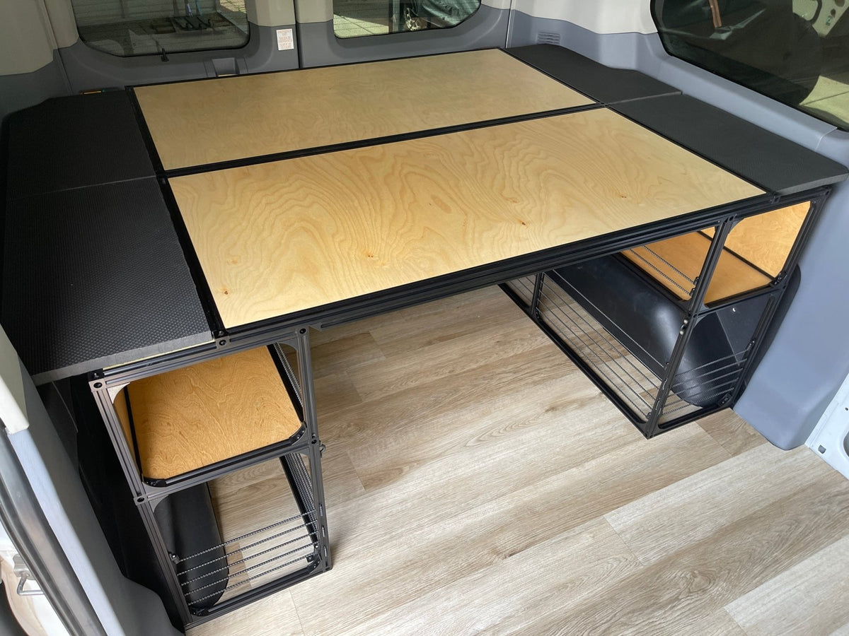 Van bed platform with light wood top and under-bed wire shelving storage units