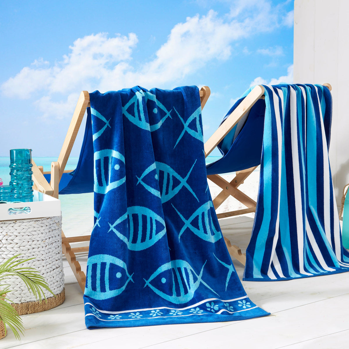 Blue cotton velour beach towel with fish print, draped over wooden beach chair