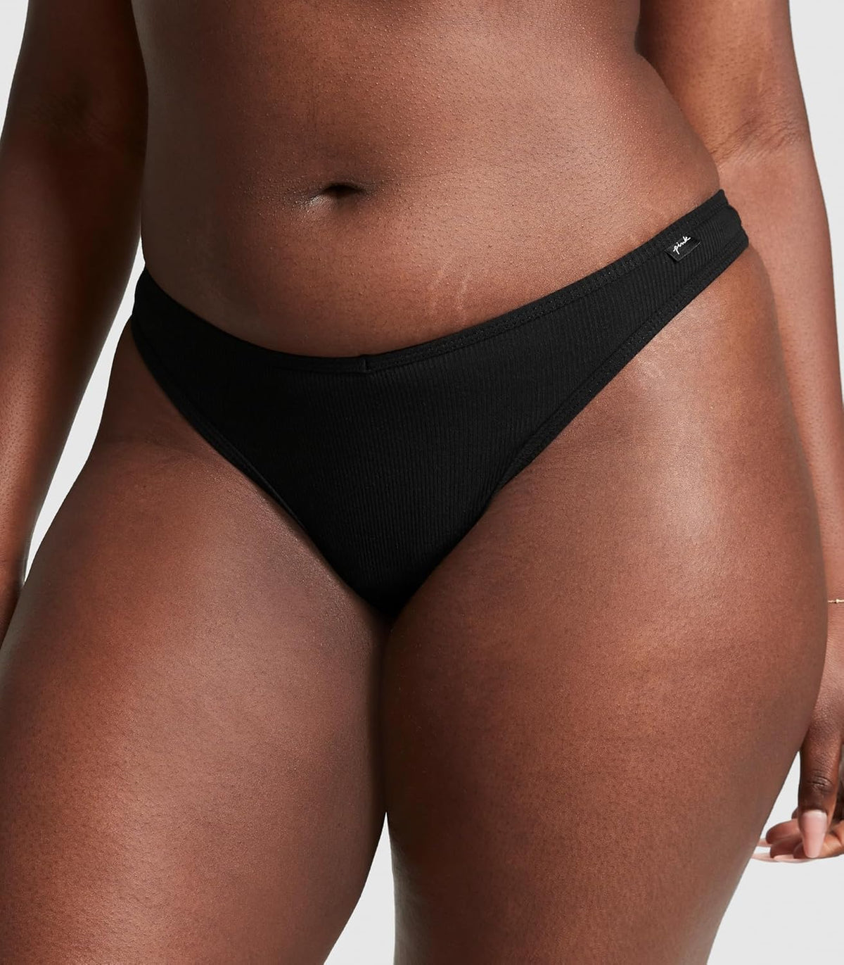 Black low-rise thong underwear with V-front and small logo tag at waistband