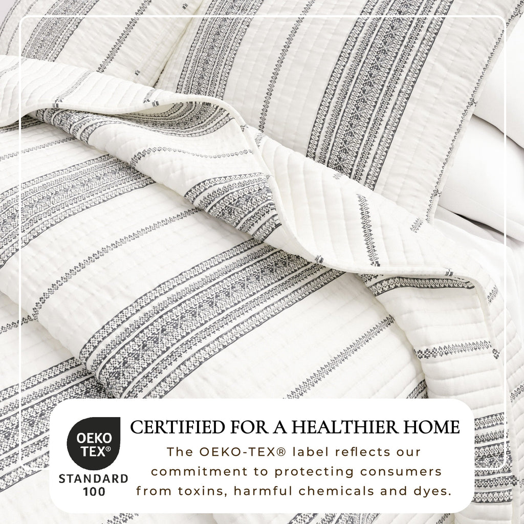 Cream and gray striped quilt close-up with stitched channels and folded edge