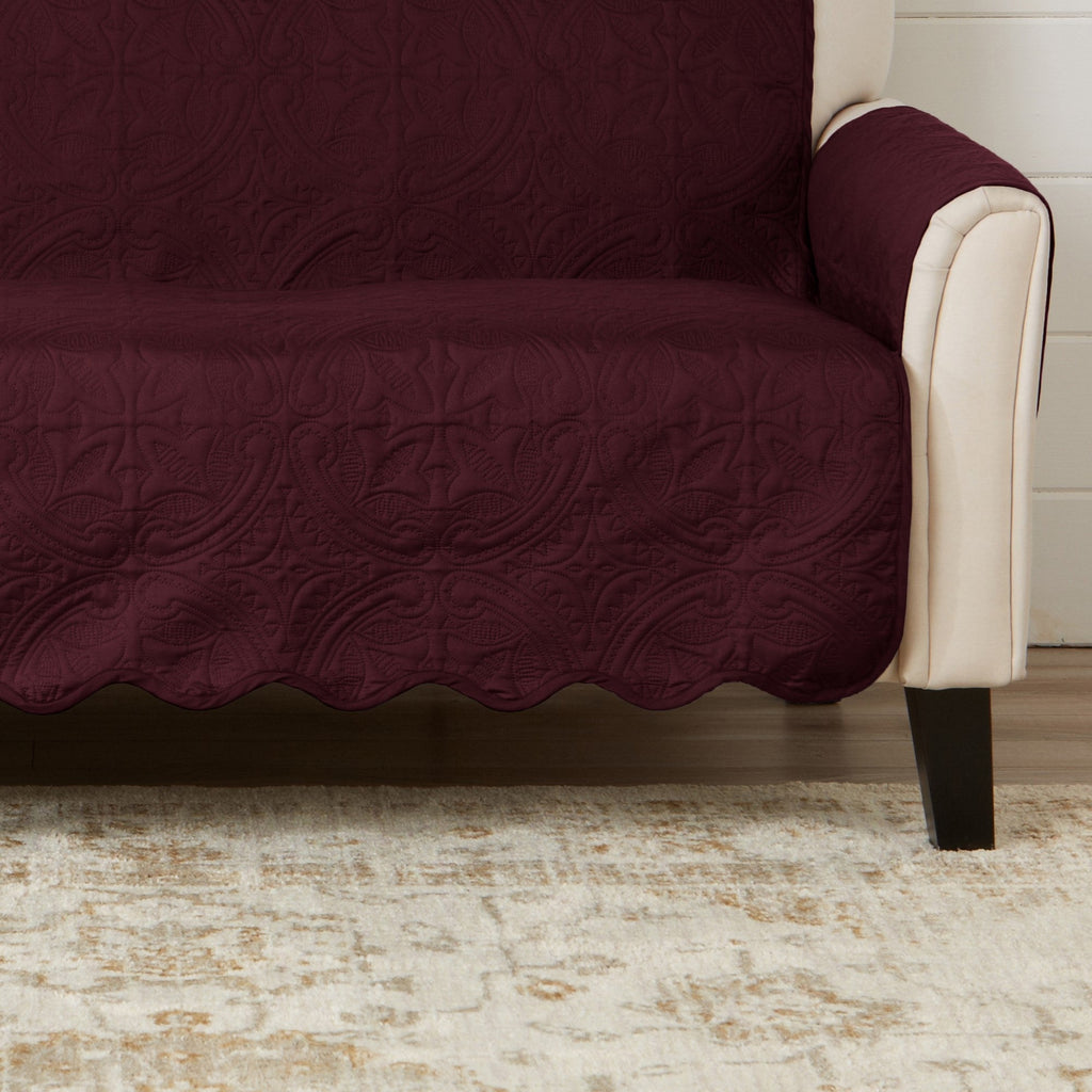 Wine red loveseat protector draped over seat and back, quilted floral and leaf pattern.
