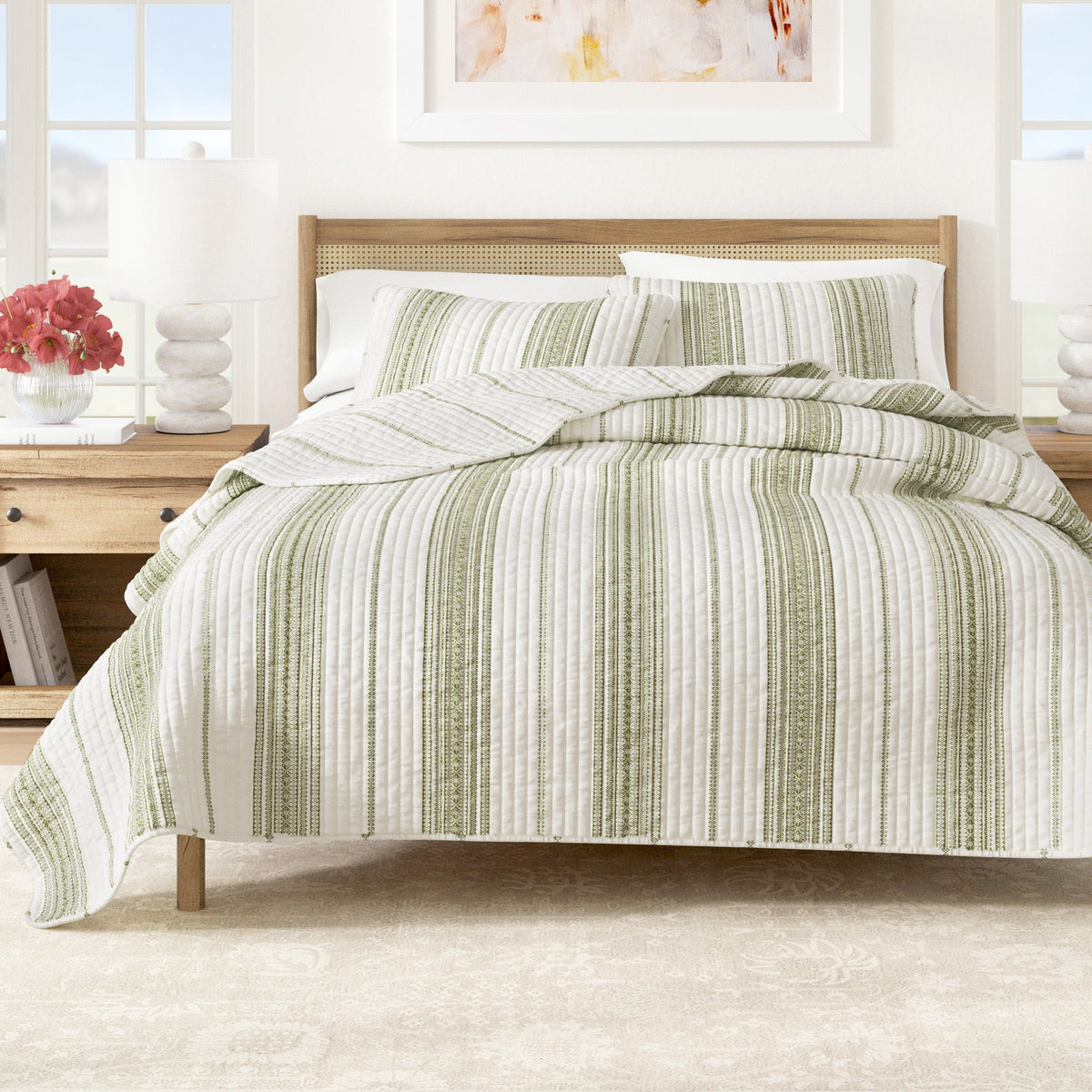Striped quilt on bed with cream base and green vertical stripe pattern.