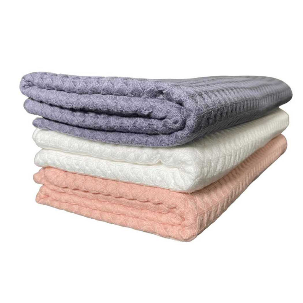 Waffle weave bath towels in charcoal gray, white, and coral folded stack