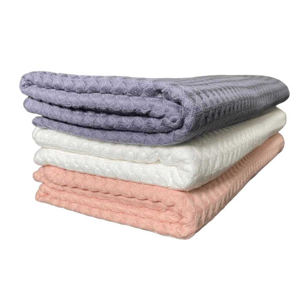 Waffle weave bath towels in charcoal gray, white, and coral folded stack
