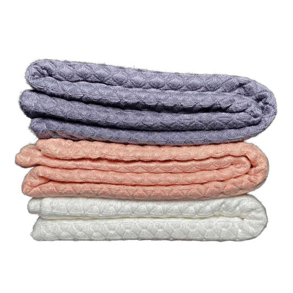 Folded waffle weave bath towels in charcoal gray, coral, and white stack