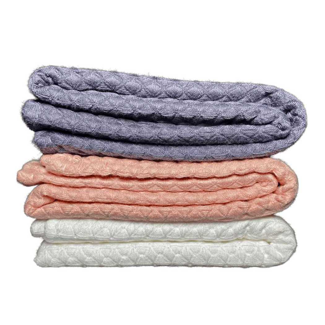 Folded waffle weave bath towels in charcoal gray, coral, and white stack