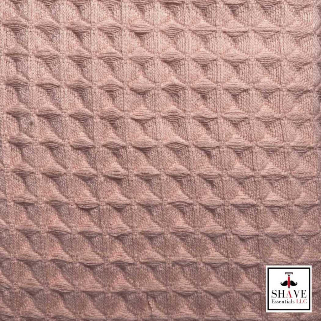 Waffle weave towel fabric close-up in light coral with embossed diamond texture