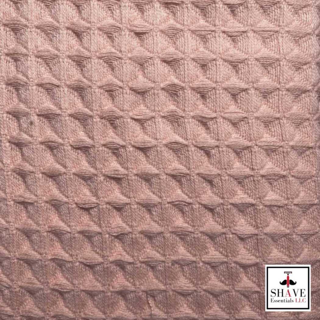 Waffle weave towel fabric close-up in light coral with embossed diamond texture