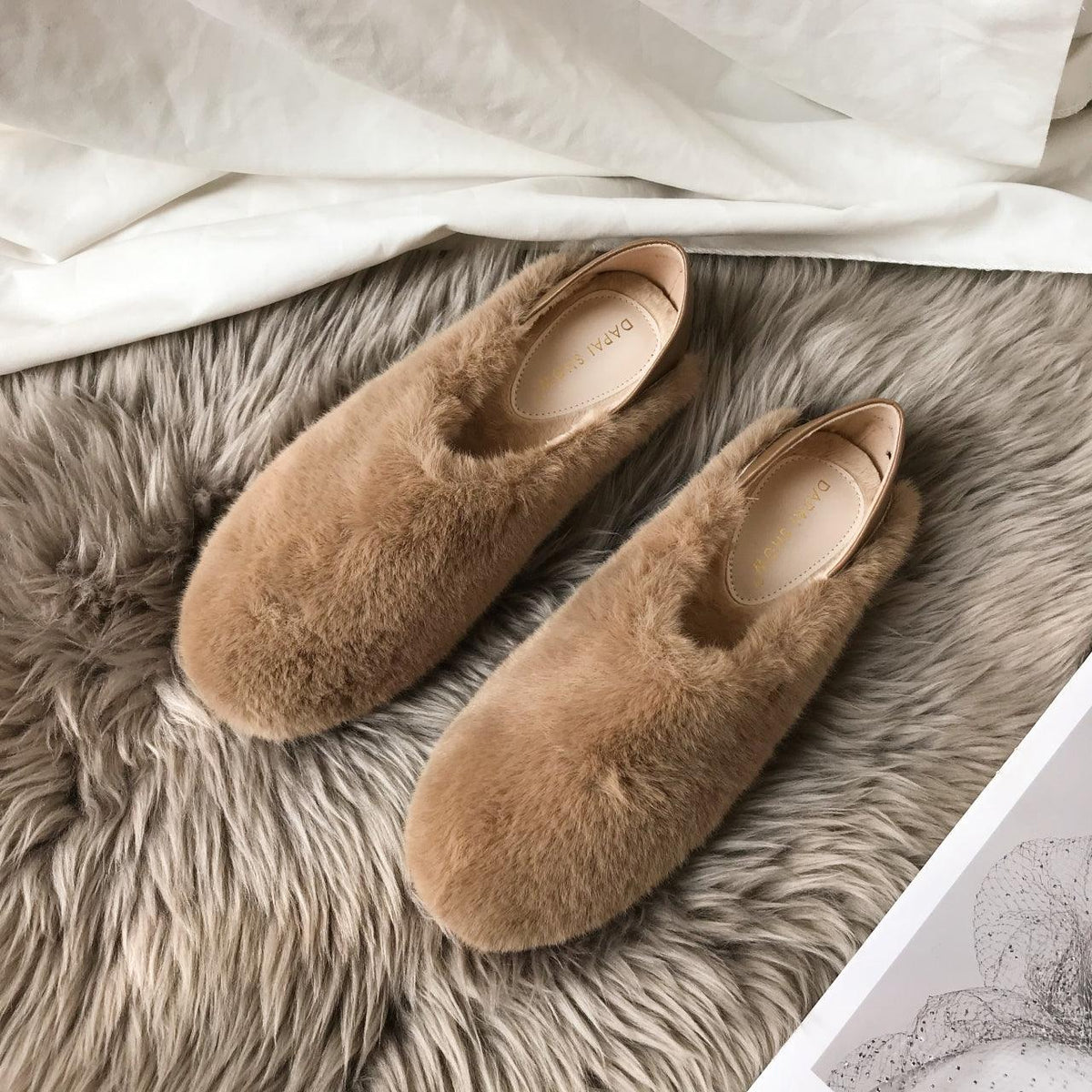 Mixed-color faux-fur slip-on loafers with round toe and tan footbed, pair on gray rug