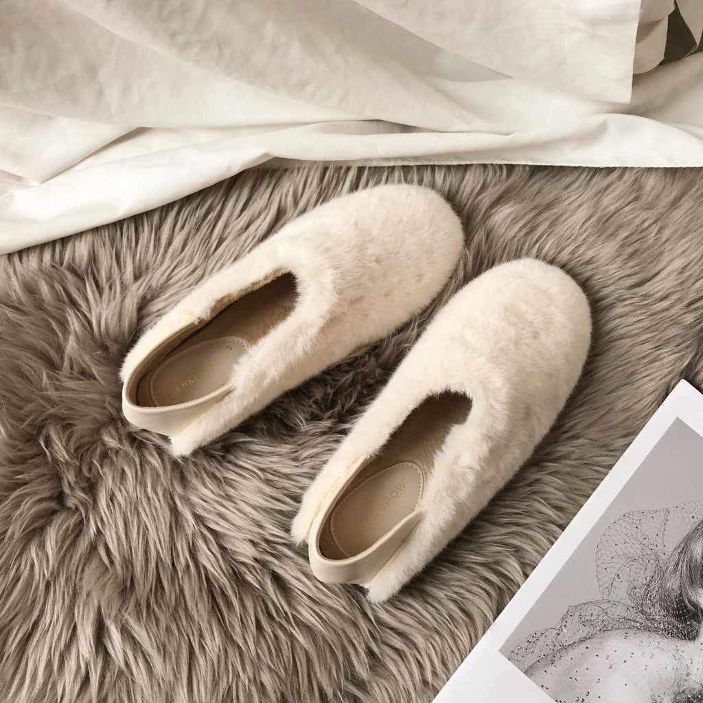 Cream white fuzzy round-toe slip-on loafers with tan footbed, pair on gray rug