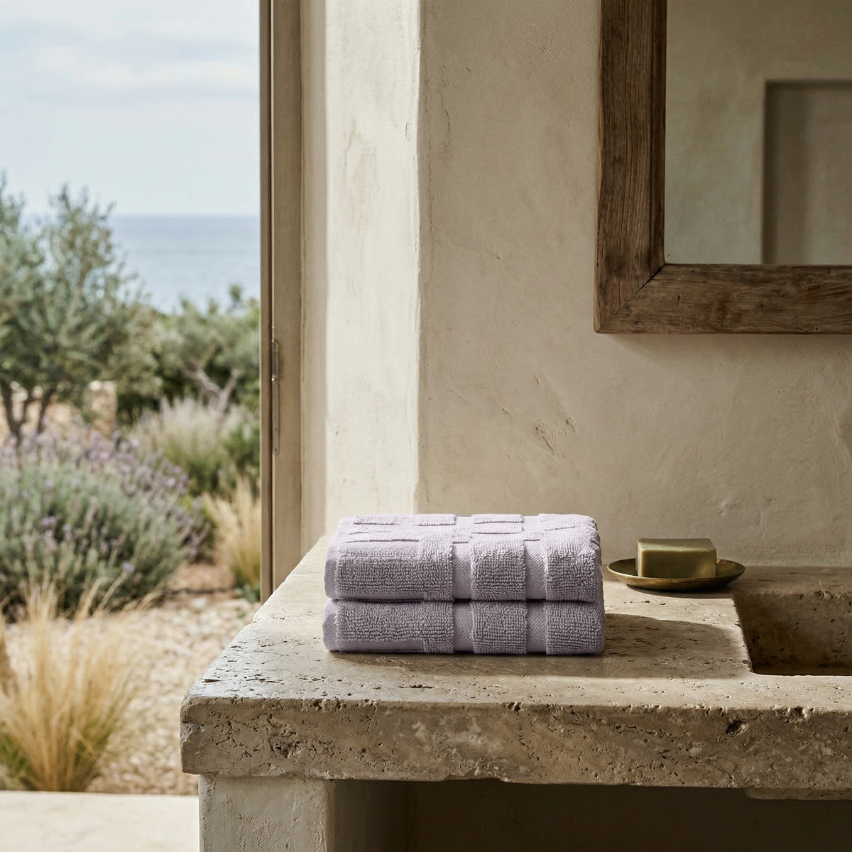 Stack of light lavender cotton towels on outdoor stone ledge
