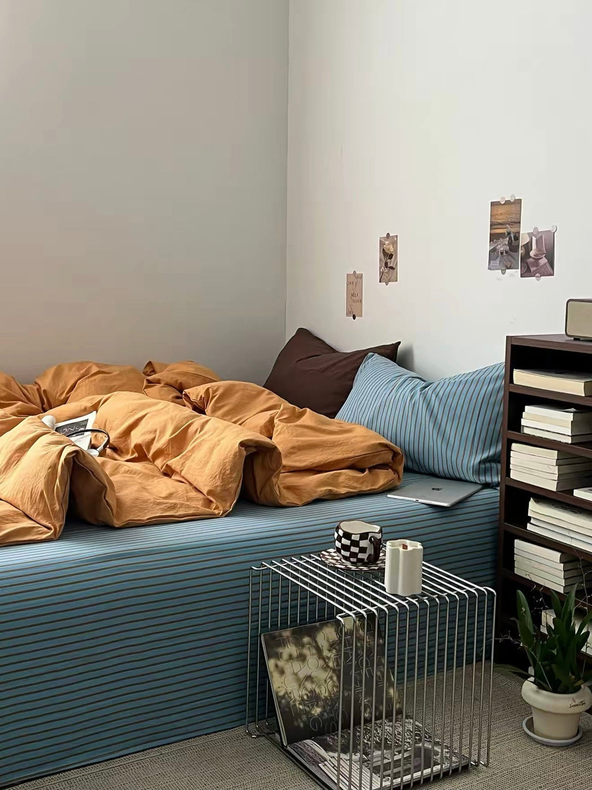 Orange bedding set on blue striped bed with two pillows and crumpled duvet