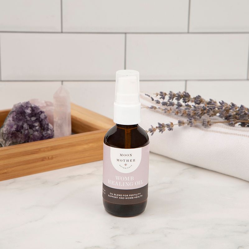 Healing oil bottle with white pump, on a countertop beside dried herbs