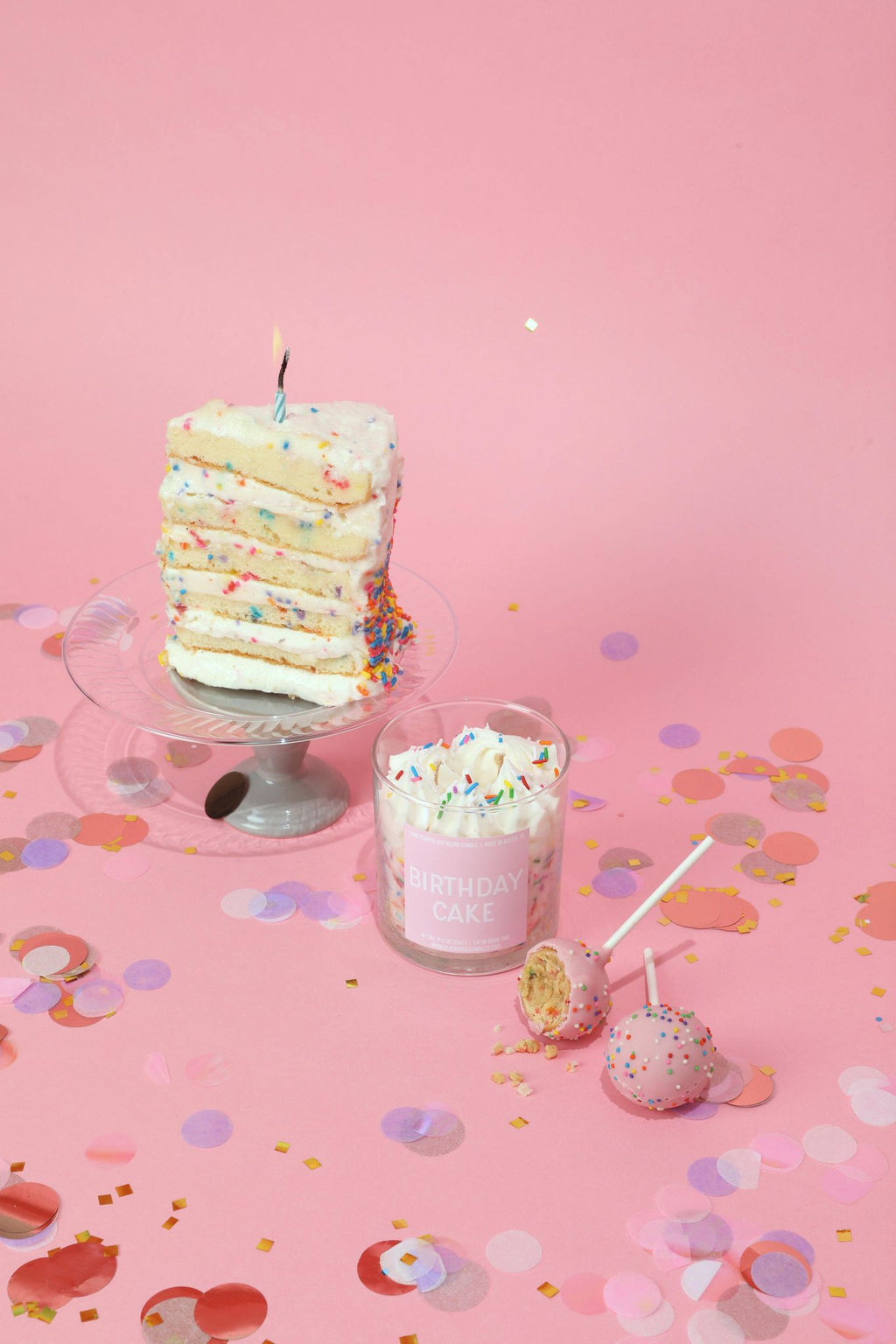 Cake-layer container candle with glass jar, colorful sprinkles and lit wick on stand