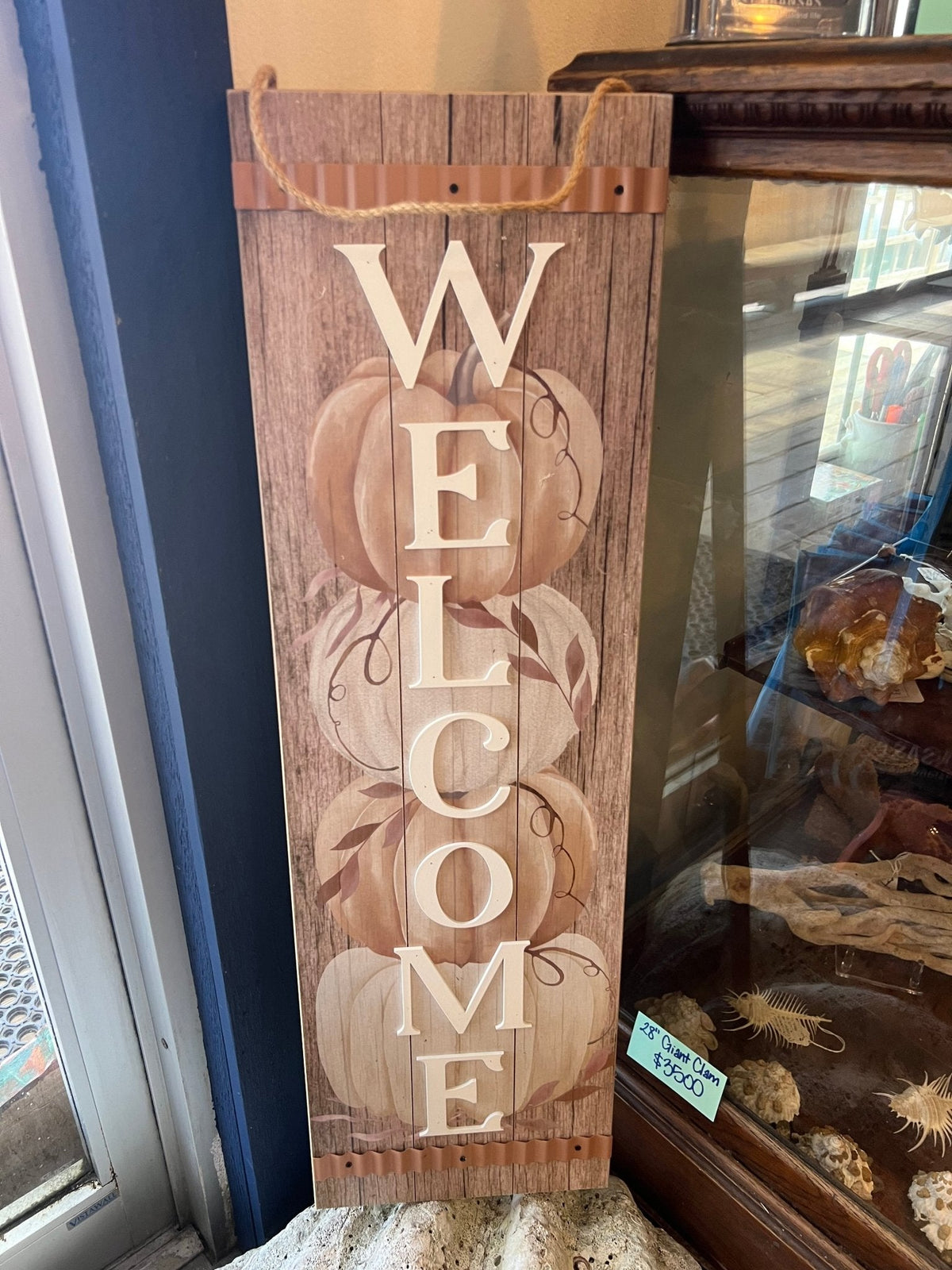 Wooden rustic Welcome sign with large vertical WELCOME letters and pumpkin outlines