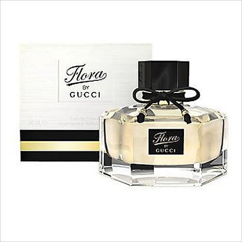 Gucci Flora glass perfume bottle with black cap and decorative gold label, box behind