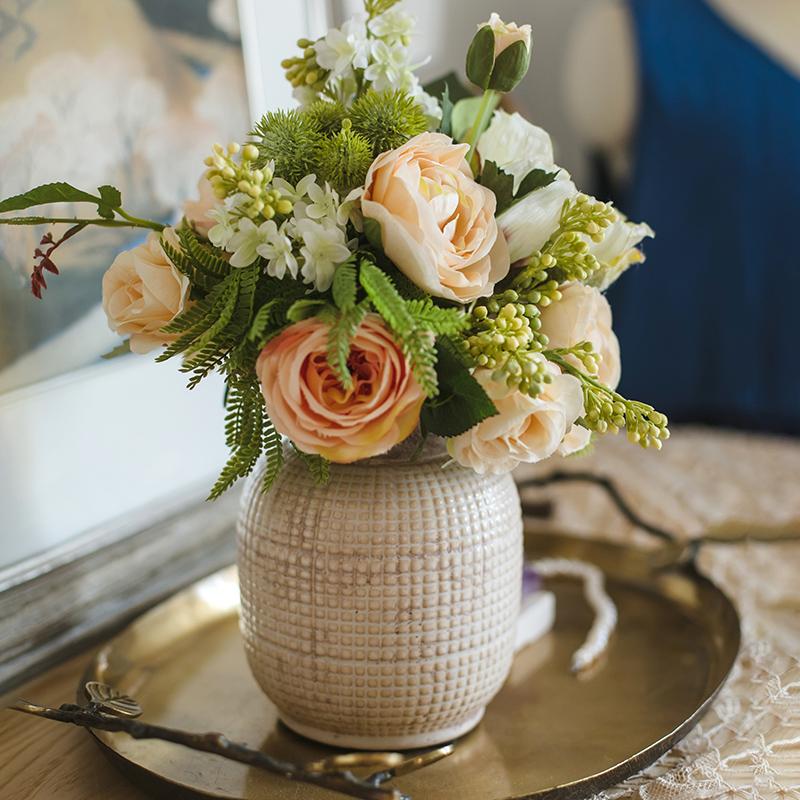 Textured ceramic jar vase holding a bouquet with narrow open neck