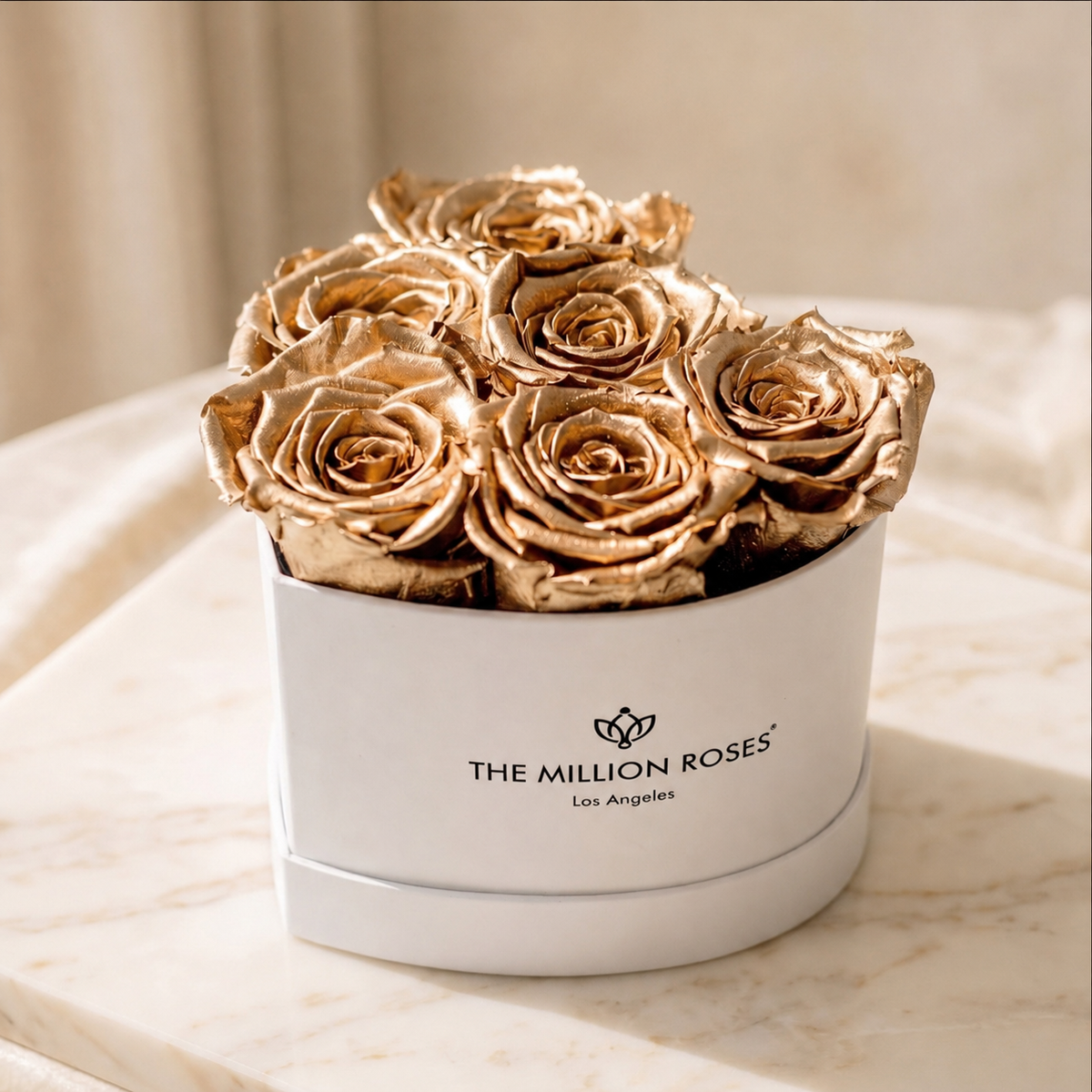 White round gift box with gold roses, front view; THE MILLION ROSES logo