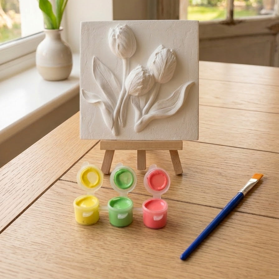 White tulip relief plaque on easel with multicolor paint pots and blue brush
