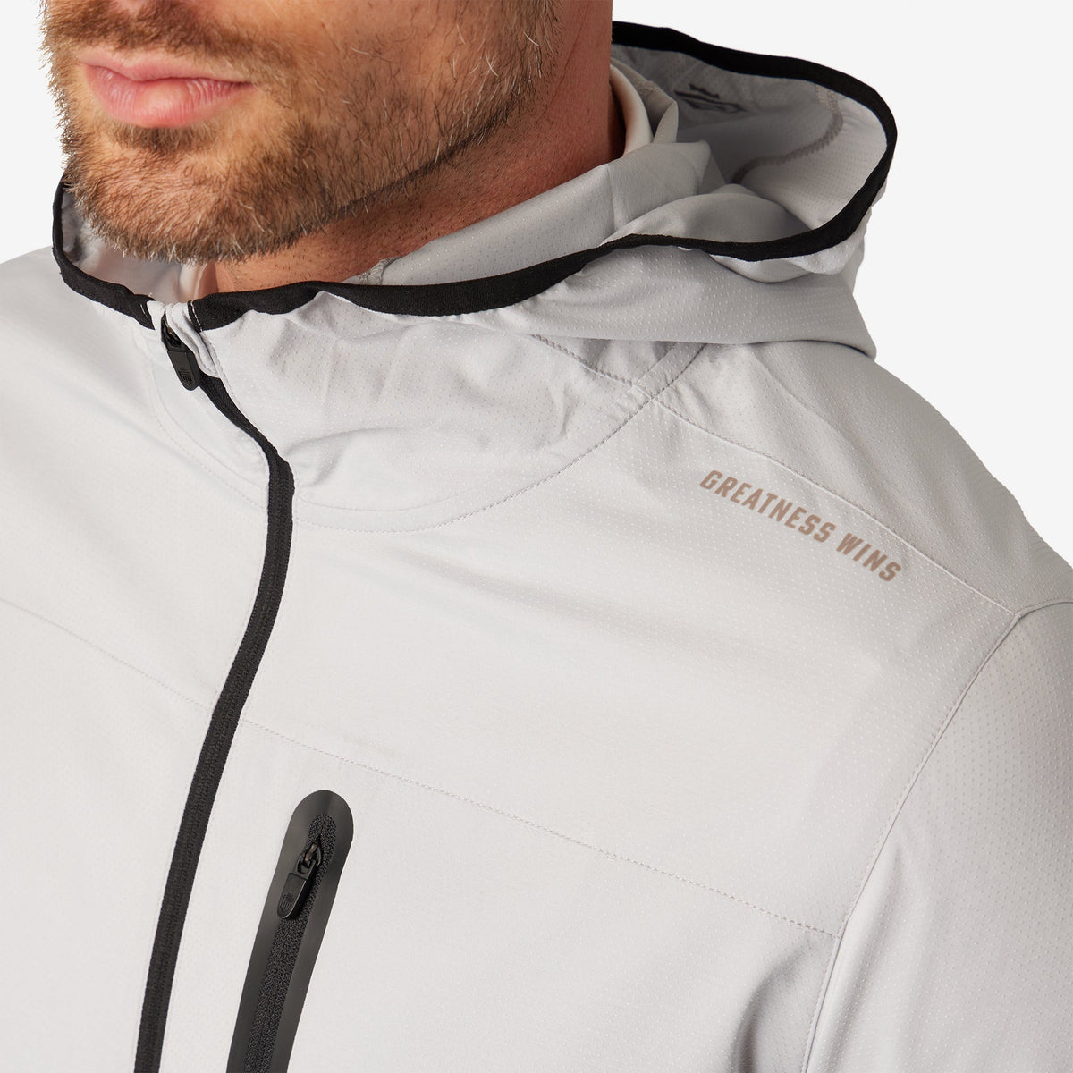 Ash gray windbreaker jacket close-up with black-trim hood and zipper pull