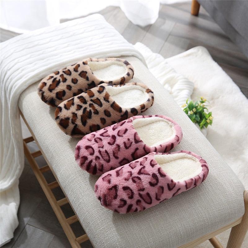 Leopard-print plush slippers stacked on a bench in tan and pink