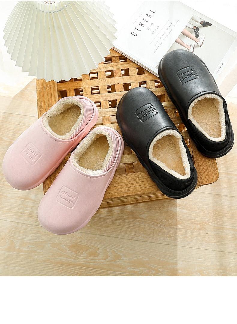 Pink and black plush-lined slip-on home slippers on wooden floor