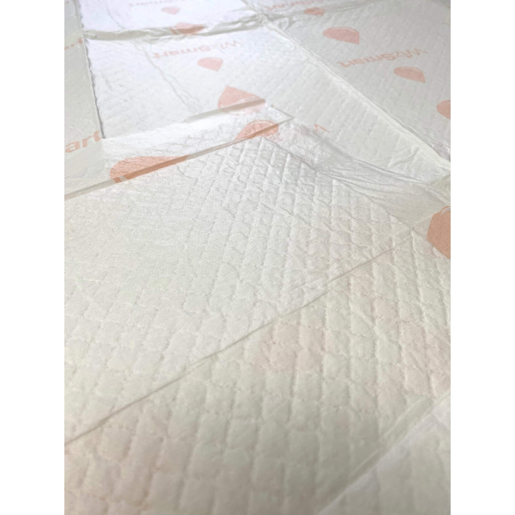 Angled view of stacked white dog training pads with paw print graphics