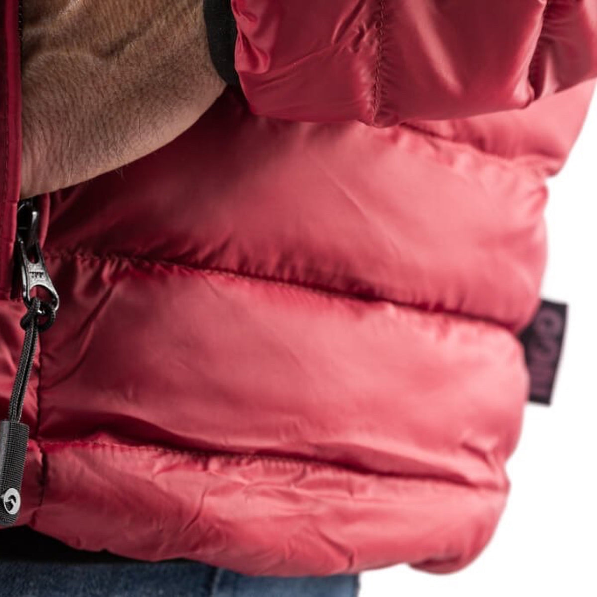 Close-up of dark red quilted heated jacket with front zipper and insulated panel stitching