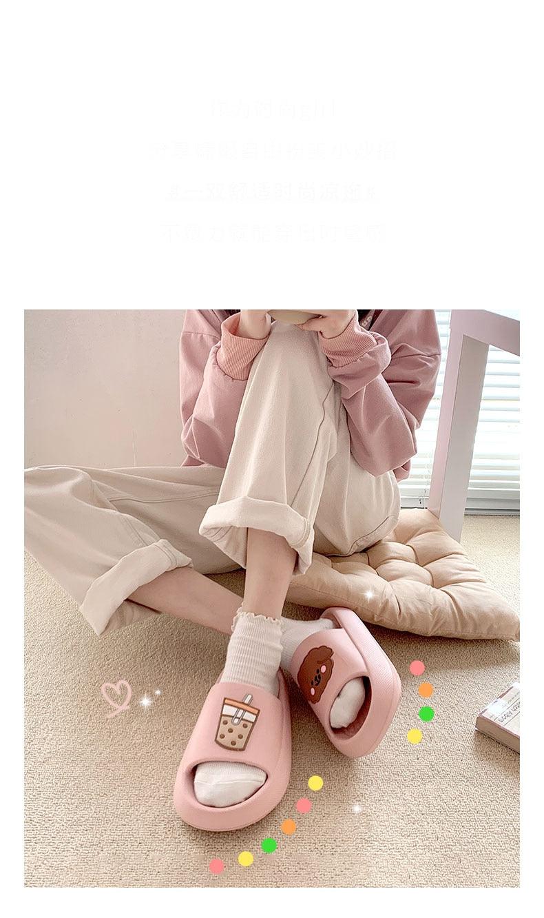 Women’s pink open-toe slide slippers with bear patch, worn with white socks