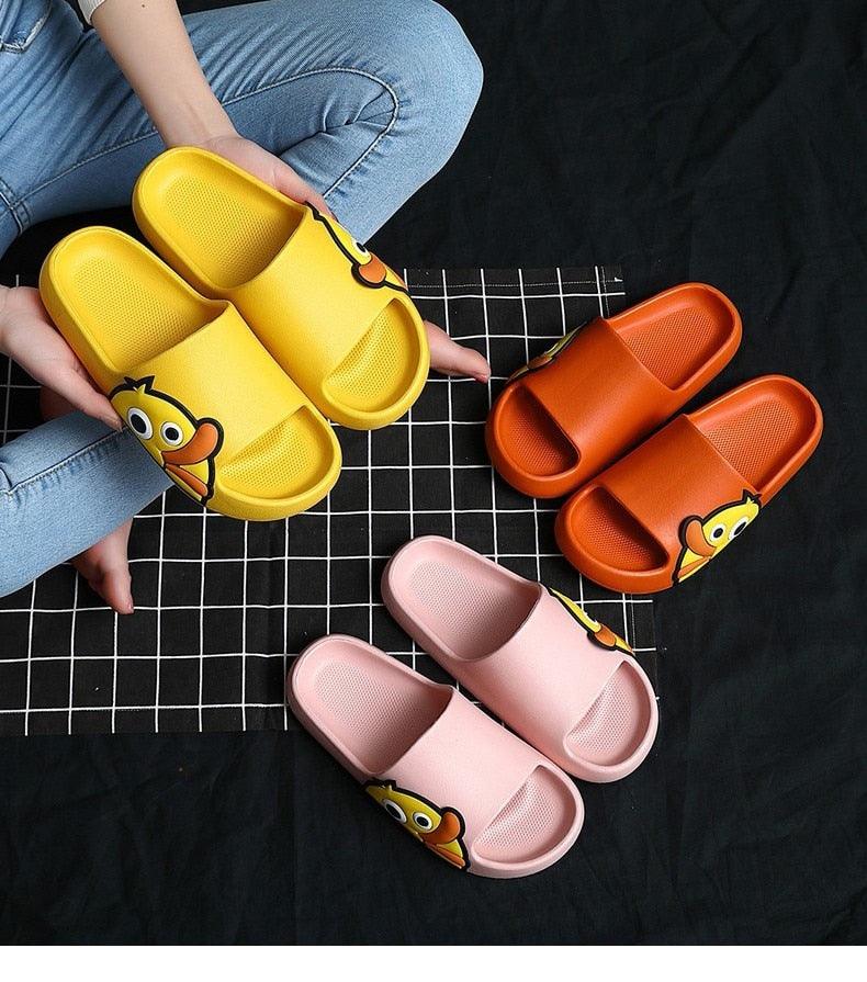 Assorted slide sandals in yellow, orange, and pink with cartoon character logos