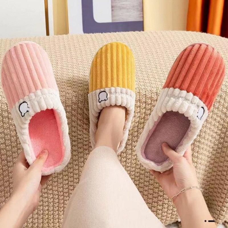 Striped knit slippers with white sherpa cuffs and bear icon on the front