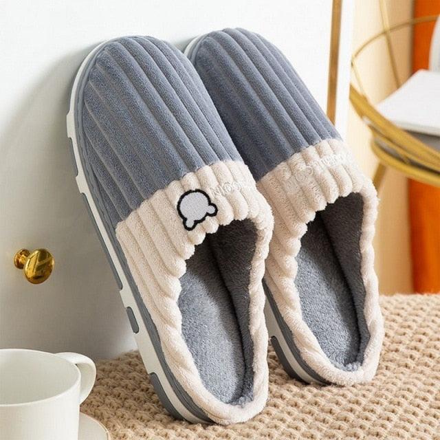 Blue ribbed slippers with white sherpa trim, open slip-on shape, and bear emblem