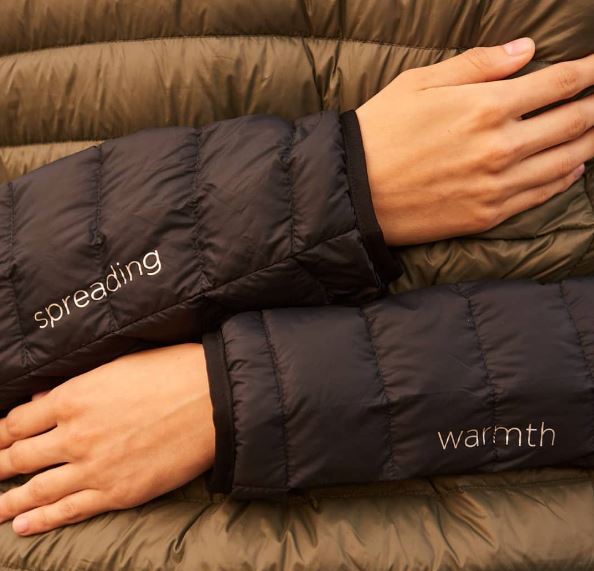 Black quilted puffer jacket sleeve detail with 'spreading' and 'warmth' prints
