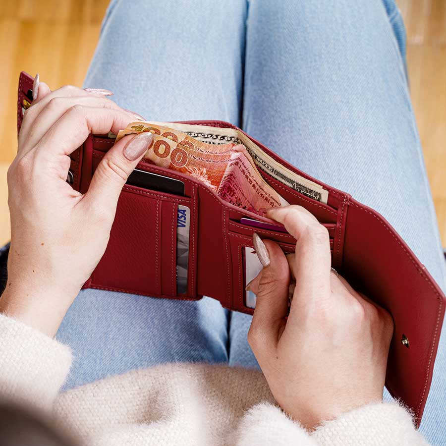 Woman holding open red trifold wallet showing card slots and cash