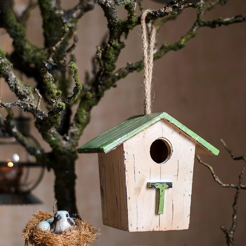 Cream wood birdhouse ornament with green roof, round entrance hole, hanging twine.