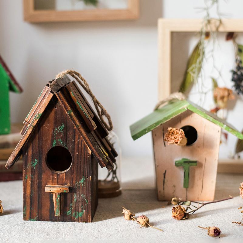 Set of rustic wood birdhouse ornaments, green and brown houses with hanging ropes.
