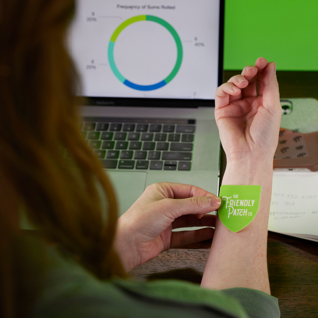 Hands applying a green energy patch to a person’s forearm